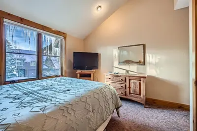 a bedroom with a bed and a tv and a window at 8712 Ski Tip Townhomes townhouse in Keystone