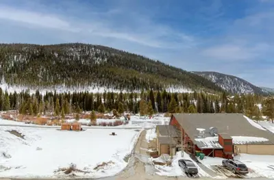 a house in the snow with a mountain in the background at 1765 Montezuma condo in Keystone
