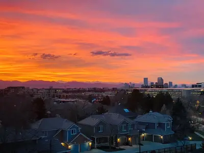 a sunset over houses in a city at dusk at Cherry Creek Condo in Denver