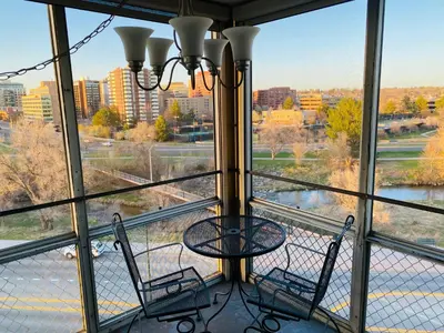 a balcony with two chairs and a table in front of a window at Cherry Creek Condo in Denver