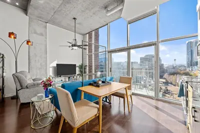 a living room with a table and chairs and large windows at 1700 Bassett, Unit 711 in Denver