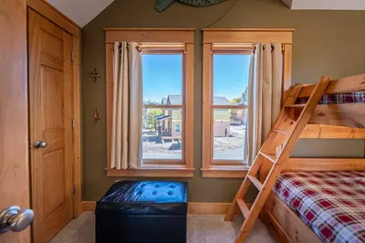 a bedroom with a bunk bed and two windows at Riverbend views ten feet away in Granby