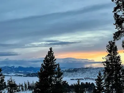 a view of a snowy mountain with trees and a sunset at Take a break from it all escape to the mountains in Grand Lake