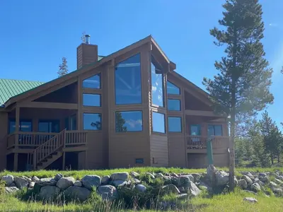 a large house with large windows and a tree at Take a break from it all escape to the mountains in Grand Lake