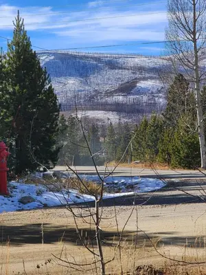 a red fire hydrant in the middle of a snow covered field at Rocky Mountain National Park Entrance one Mile in Grand Lake