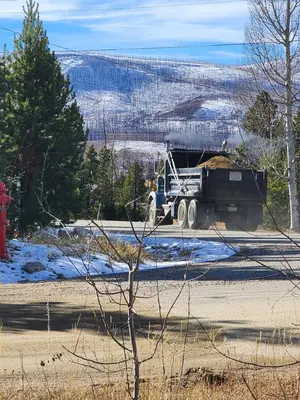 a dump truck driving down a road in the snow at Rocky Mountain National Park Entrance one Mile in Grand Lake