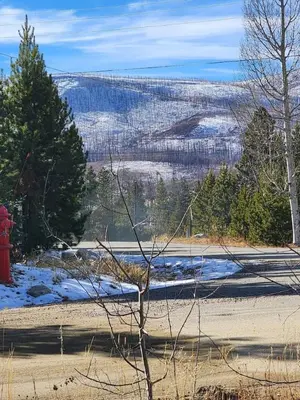 a red fire hydrant in the middle of a snow covered field at Rocky Mountain National Park Entrance one Mile in Grand Lake