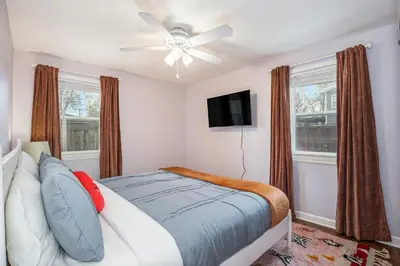 a bedroom with a bed with a ceiling fan and windows at The Funky Flamingo - HOT TUB - BBQ - Fire Pit in Arvada