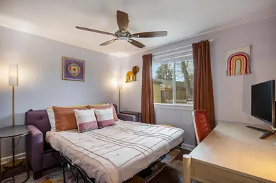 a bedroom with a bed and a desk and a tv at The Funky Flamingo - HOT TUB - BBQ - Fire Pit in Arvada