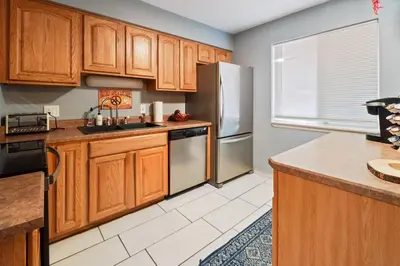 a kitchen with wooden cabinets and a stainless steel refrigerator at Vibrant and spacious 3 level home by park in Northglenn
