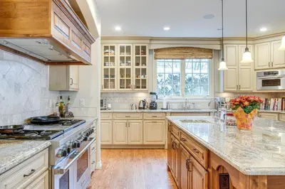 a kitchen with white cabinets and marble counter tops at Walk to DU, Dining and Parks Spacious Denver Home! in Denver