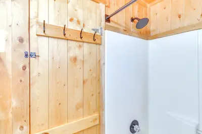 a bathroom with a wooden wall with a door at Mtn-View Haven with Hot Tub 9 Mi to Dtwn Bailey in Bailey