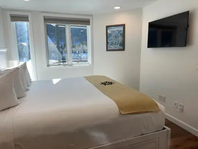 a bedroom with a large bed with a tv on the wall at Beautiful Renovated 1BR Lakeside Condo condo in Keystone