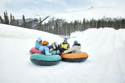 a group of people riding on a tube in the snow at Lakeside, spacious, modern 2BR - sleeps up to 8 condo in Keystone