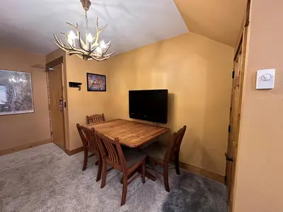 a dining room with a table with chairs and a television at Lakeside, spacious, modern 2BR - sleeps up to 8 condo in Keystone