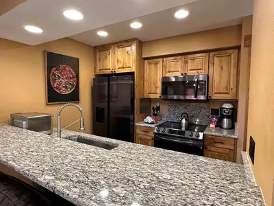 a kitchen with wooden cabinets and a granite counter top at Lakeside, spacious, modern 2BR - sleeps up to 8 condo in Keystone