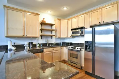 a kitchen with wooden cabinets and a stainless steel refrigerator at La Riva Del Lago Condo: Downtown, Close to Everything in Dillon