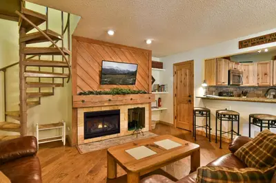 a living room with a fireplace and a stair case at Flying Dutchman Mountainside Condo: Pool/Hot Tub in Keystone