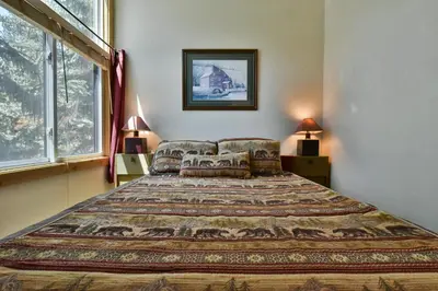 a bedroom with a large bed and two windows at Flying Dutchman Mountainside Condo: Pool/Hot Tub in Keystone