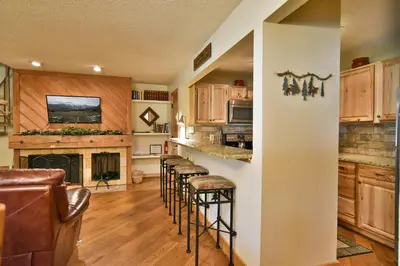 a kitchen with a row of bar stools at Flying Dutchman Mountainside Condo: Pool/Hot Tub in Keystone