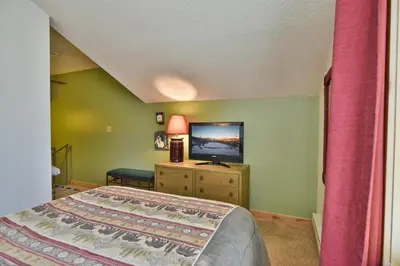 a bedroom with a bed and a flat screen tv at Flying Dutchman Mountainside Condo: Pool/Hot Tub in Keystone