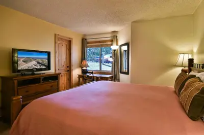 a bedroom with a large bed and a flat screen tv at Flying Dutchman Mountainside Condo: Pool/Hot Tub in Keystone