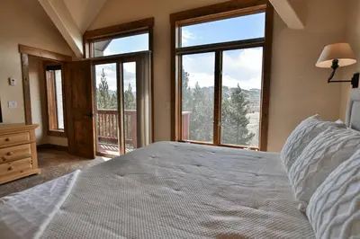a bedroom with a large bed and large windows at Prospect Point Retreat: Lakeside Townhome, Mountain Views in Frisco