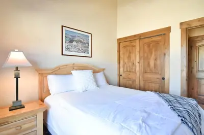a bedroom with a white bed and a lamp at Prospect Point Retreat: Lakeside Townhome, Mountain Views in Frisco
