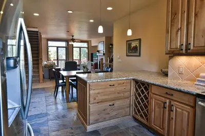 a kitchen with wooden cabinets and a dining room with a table at Prospect Point Retreat: Lakeside Townhome, Mountain Views in Frisco