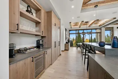 a kitchen with wooden cabinets and a bar with chairs at Brand New Eagles Nest Property in Silverthorne
