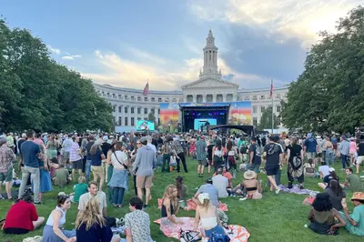 a crowd of people sitting on the grass in front of a building at 1 bed apartment with parking - Denver Museum District Walk to Convention Center, Capital, museums and shops in Denver