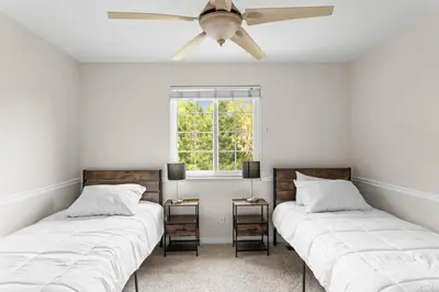two beds in a room with a ceiling fan at Cozy Central Aurora Home in Aurora