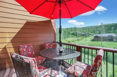 a table and chairs on a balcony with a red umbrella at Majestic Views - Steps to the Trails! in Fraser