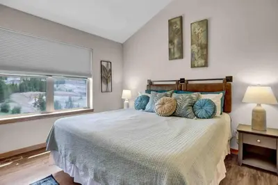 a bedroom with a bed with blue pillows and a window at Majestic Views - Steps to the Trails! in Fraser