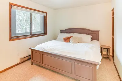 a bedroom with a bed with white sheets and a window at Walk to Winter Park Resort Condo with Hot Tub! in Winter Park