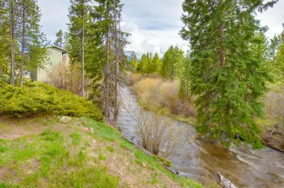 a river in a forest with a house and trees at Pool and 3 Hot Tubs Winter Park Condo on Bus Line in Winter Park
