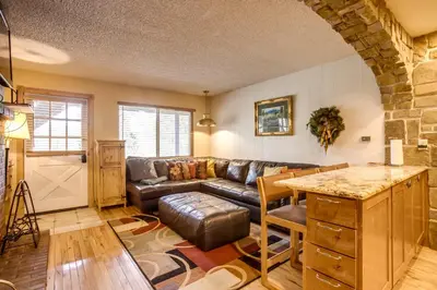 a living room with a leather couch and a table at Pool and 3 Hot Tubs Winter Park Condo on Bus Line in Winter Park