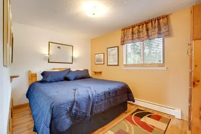 a bedroom with a bed with blue sheets and a window at Pool and 3 Hot Tubs Winter Park Condo on Bus Line in Winter Park