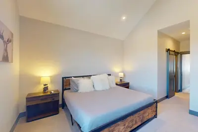 a bedroom with a bed with two night stands and two lamps at Mountain Bliss Retreat in Granby in Granby