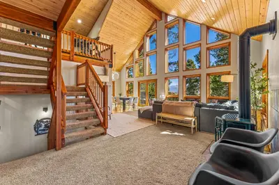 a living room with a wooden ceiling and a spiral staircase at Tranquil Trails in Granby