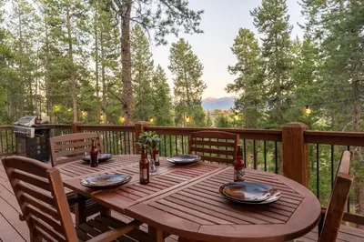 a wooden table on a deck with chairs and a tableablish at Tranquil Trails in Granby