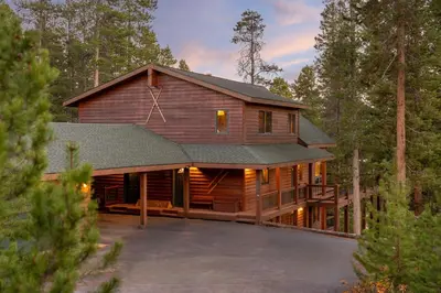 a large wooden house in the woods at Tranquil Trails in Granby