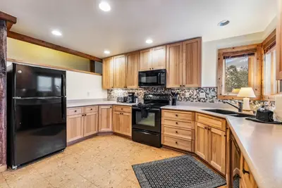 a kitchen with wooden cabinets and black appliances at Dillon Retreat with Lake Views and Private Hot Tub in Dillon