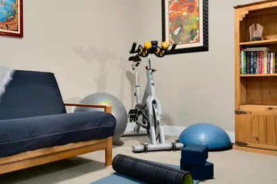 a living room with a exercise bike and a chair at Old Town Escape with King Bed, Dog-Friendly in Fort Collins