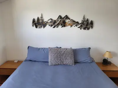 a bedroom with a bed with blue sheets and trees on the wall at Best Location in Downtown Winter Park in Winter Park