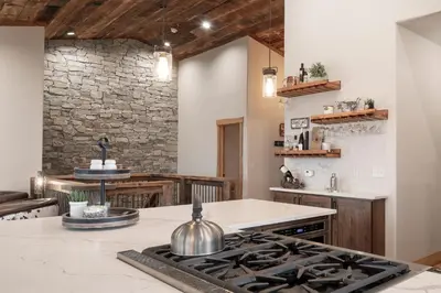 a kitchen with a stone wall and a stove at Luxurious Chalet - Epic Views, Hot Tub, Gym, Game Room, & 4k Projector in Grand Lake in Grand Lake