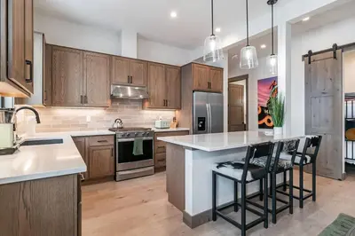 a kitchen with wooden cabinets and a kitchen island with bar stools at Elevated Vibes in Fraser