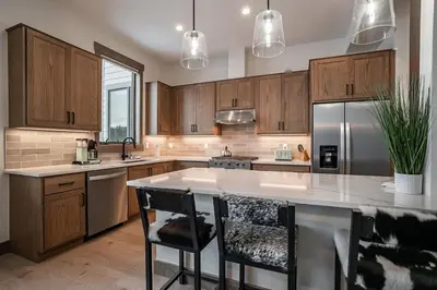 a kitchen with wooden cabinets and a large island with bar chairs at Elevated Vibes in Fraser