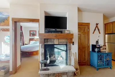 a living room with a fireplace with a flat screen tv at Horse Lodges 5-102 in Granby