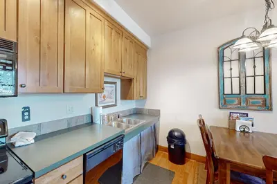 a kitchen with wooden cabinets and a sink and a table at Horse Lodges 5-102 in Granby
